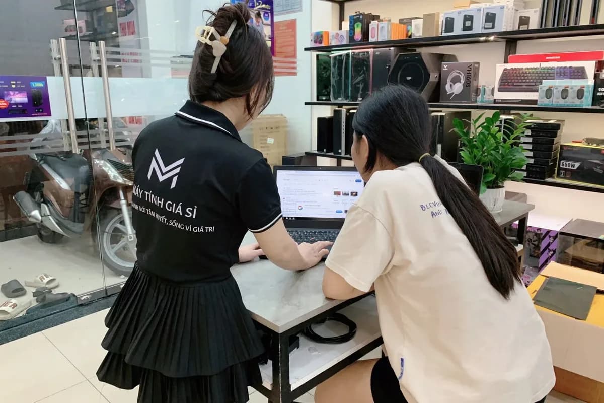 Nhân viên Máy Tính Giá Sỉ ngồi cùng khách xem thông tin trên laptop